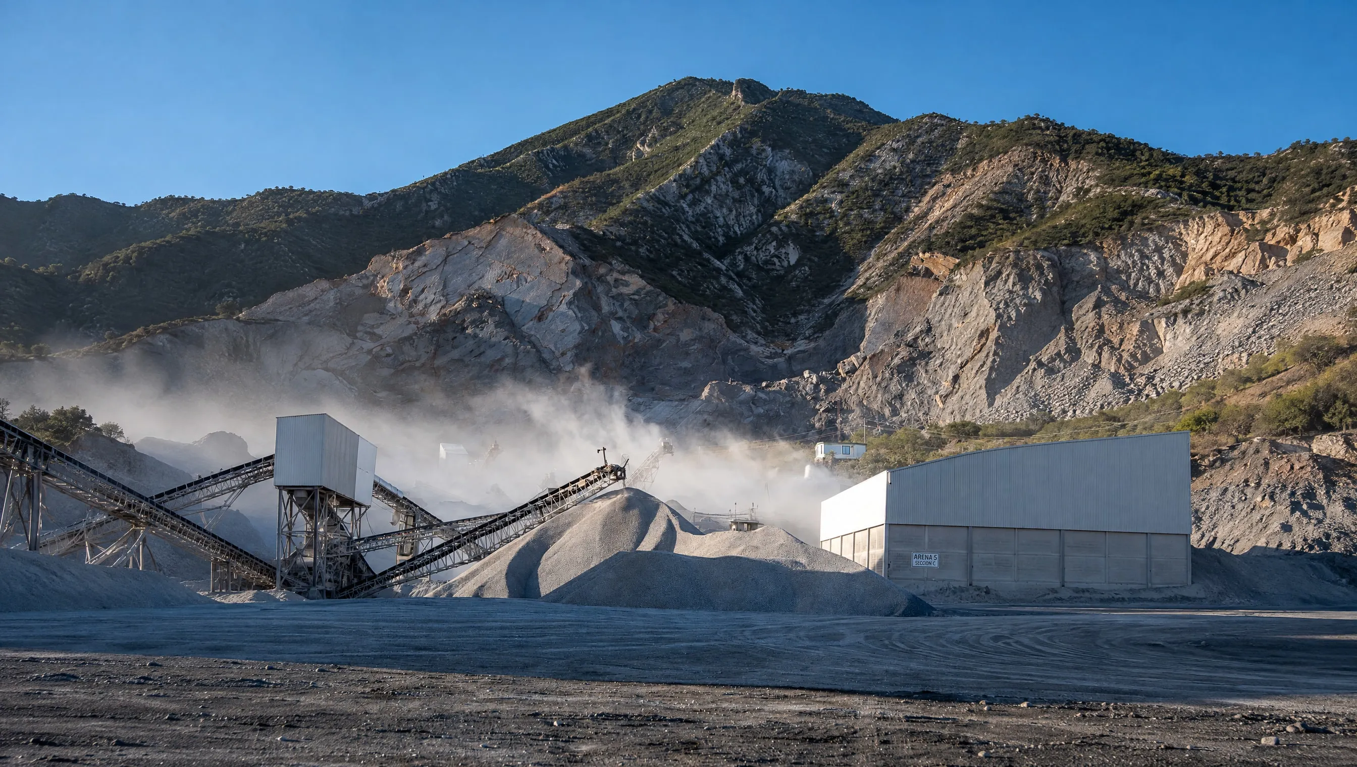 Planta de trituración, bandas y montañas de material al pie de la sierra
