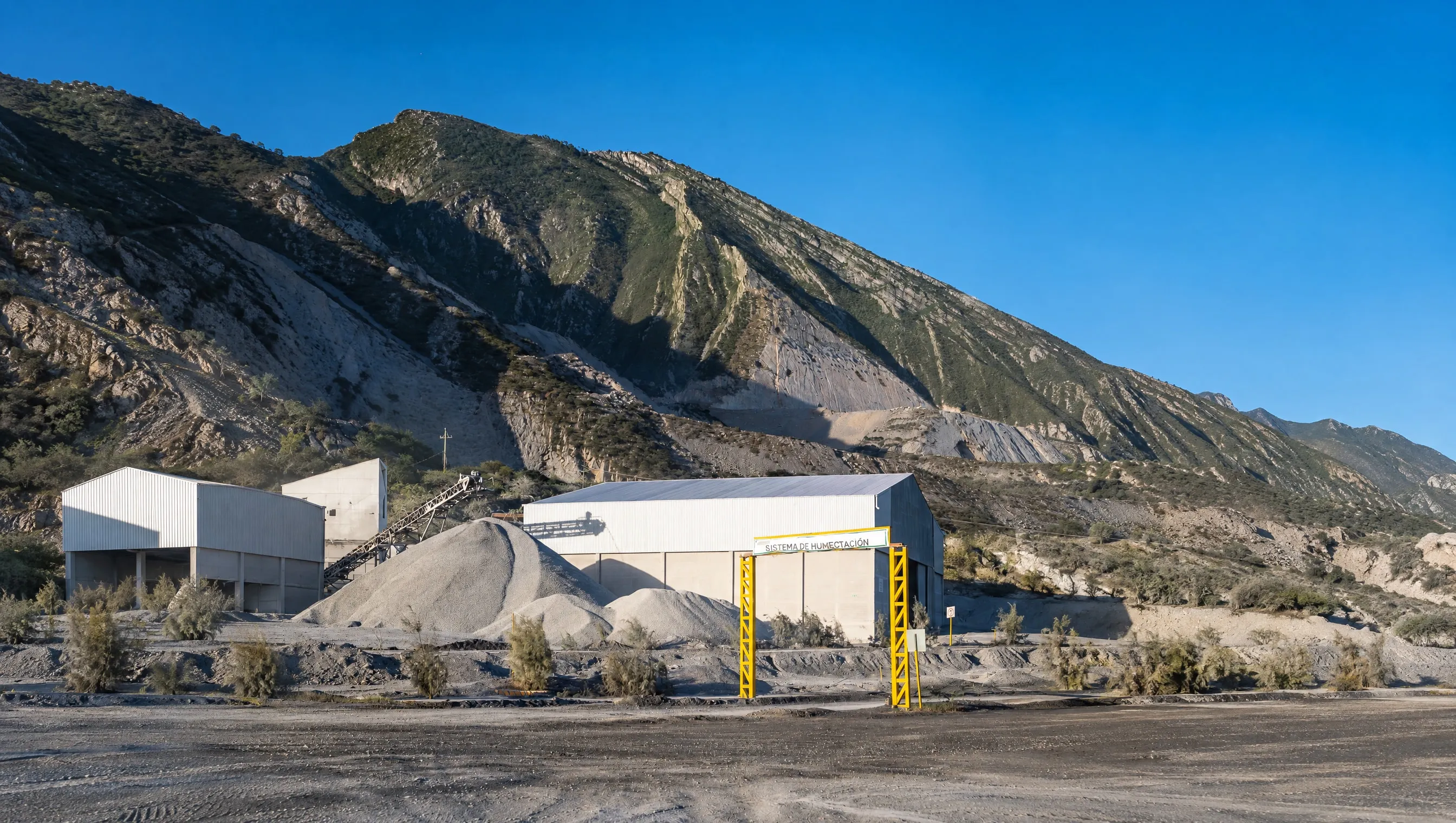 Naves de la planta y arco amarillo del sistema de humectación al pie de la sierra